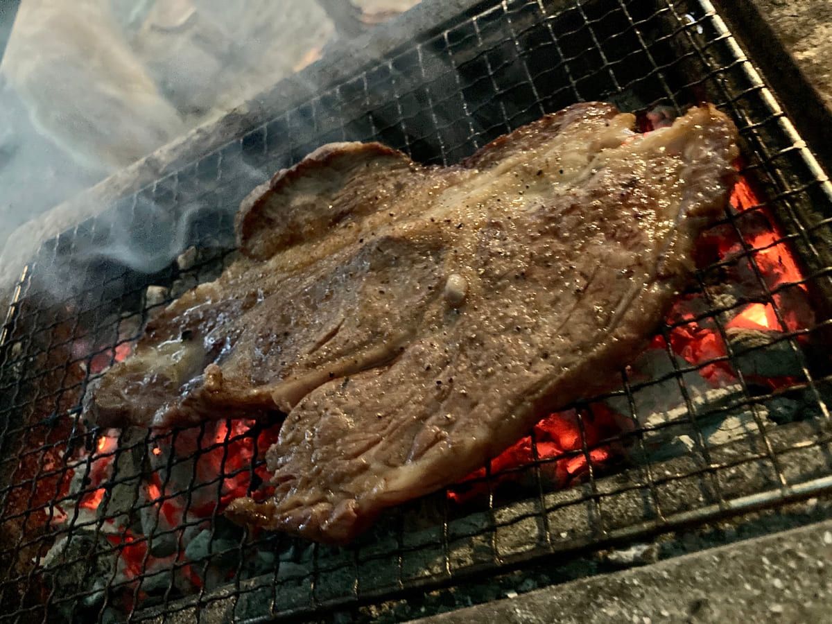暗くなりはじめた林間と、灯りのともるテント